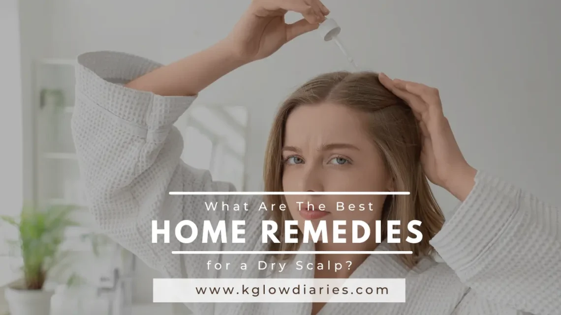 The image shows a woman with shoulder-length brown hair wearing a white textured bathrobe, looking directly at the camera with a neutral expression. She is holding a glass dropper over her head, applying a clear liquid to her scalp while using her other hand to part her hair. In the center of the image, there is a large text overlay that reads: What Are The Best HOME REMEDIES for a Dry Scalp? www.kglowdiaries.com
