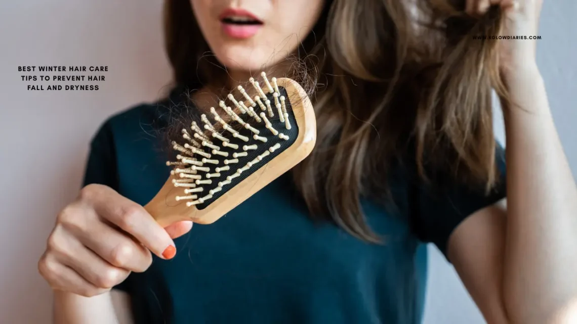 This image shows a person looking concerned while holding a wooden hairbrush that has several strands of tangled hair caught in the bristles. The person has long brown hair and is wearing a dark green t-shirt. There is text on the left side of the image that reads: "BEST WINTER HAIR CARE TIPS TO PREVENT HAIR FALL AND DRYNESS". In the top right corner, the website "WWW.KGLOWDIARIES.COM" is displayed.