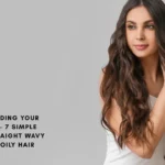 A woman with long, voluminous wavy brown hair looking to the side against a grey background, illustrating the "wavy" hair type category.