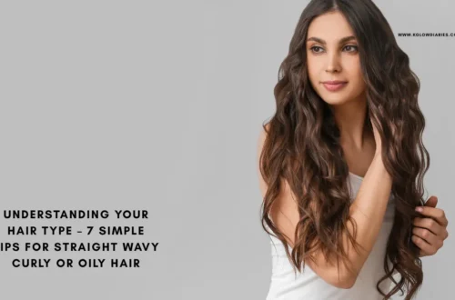 A woman with long, voluminous wavy brown hair looking to the side against a grey background, illustrating the "wavy" hair type category.