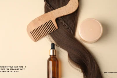 A top-down view of hair care essentials featuring a long strand of wavy brunette hair with a small braid, a wooden wide-tooth comb, an amber glass dropper bottle, and a round tan cosmetic jar on a neutral background.